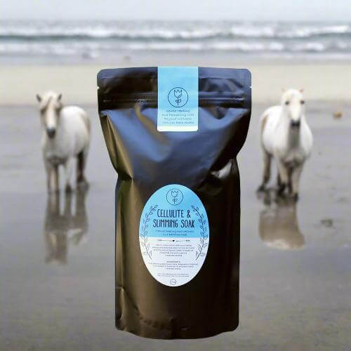 Body contouring soak with grapefruit essential oils in a black pouch by the beach with horses in the background.