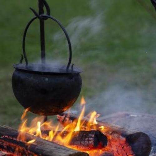 Natural insect repellent spray useful to apply when sitting around an open campfire with a black pot.
