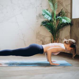 A person practicing yoga in a plank pose on a yoga mat, highlighting the calming yoga mat spray for mat care.