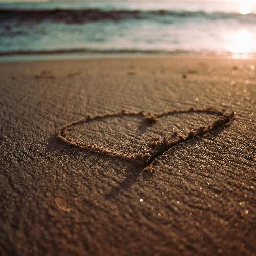 Heart drawn in sand on a beach during sunset, symbolizing love and tranquility as depicted in the bath salt gift sets.