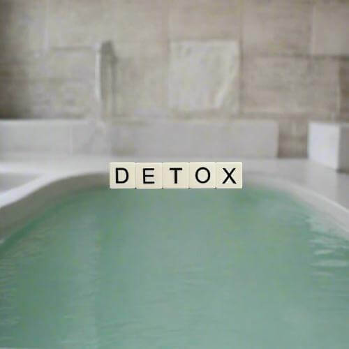 ZestySpiritz Detox and Cleansing Bath Soak 700g in a clear jar with a spoon, surrounded by herbs and bath elements.