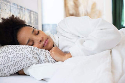 Woman sleeping peacefully with herbal sleep support capsules on bedside table for restful nights.
