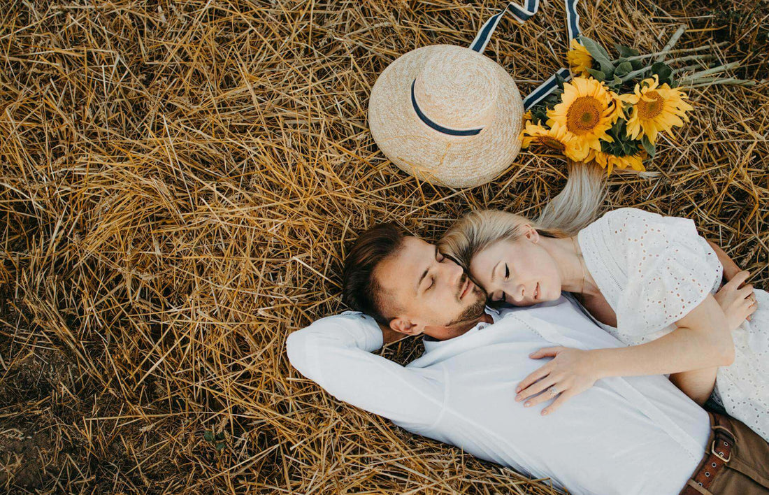 Couple lying on straw with sunflowers, enjoying peaceful moments together and embracing natural ways to improve sleep.
