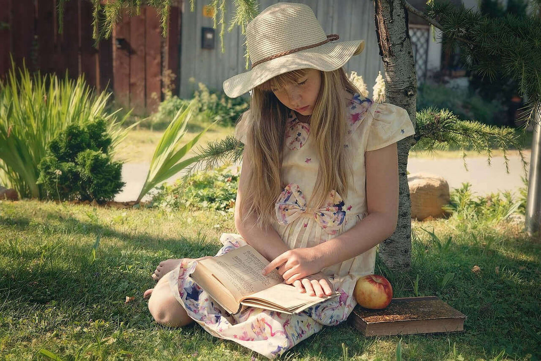 Girl reading a book under a tree, showcasing the importance of natural supplements for kids focus.