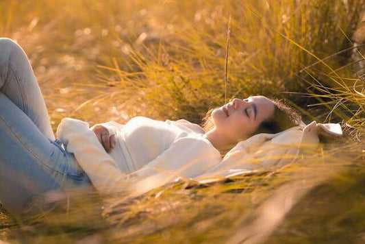 A woman practicing natural sleep rituals South Africa, relaxing on grass in a serene outdoor setting.