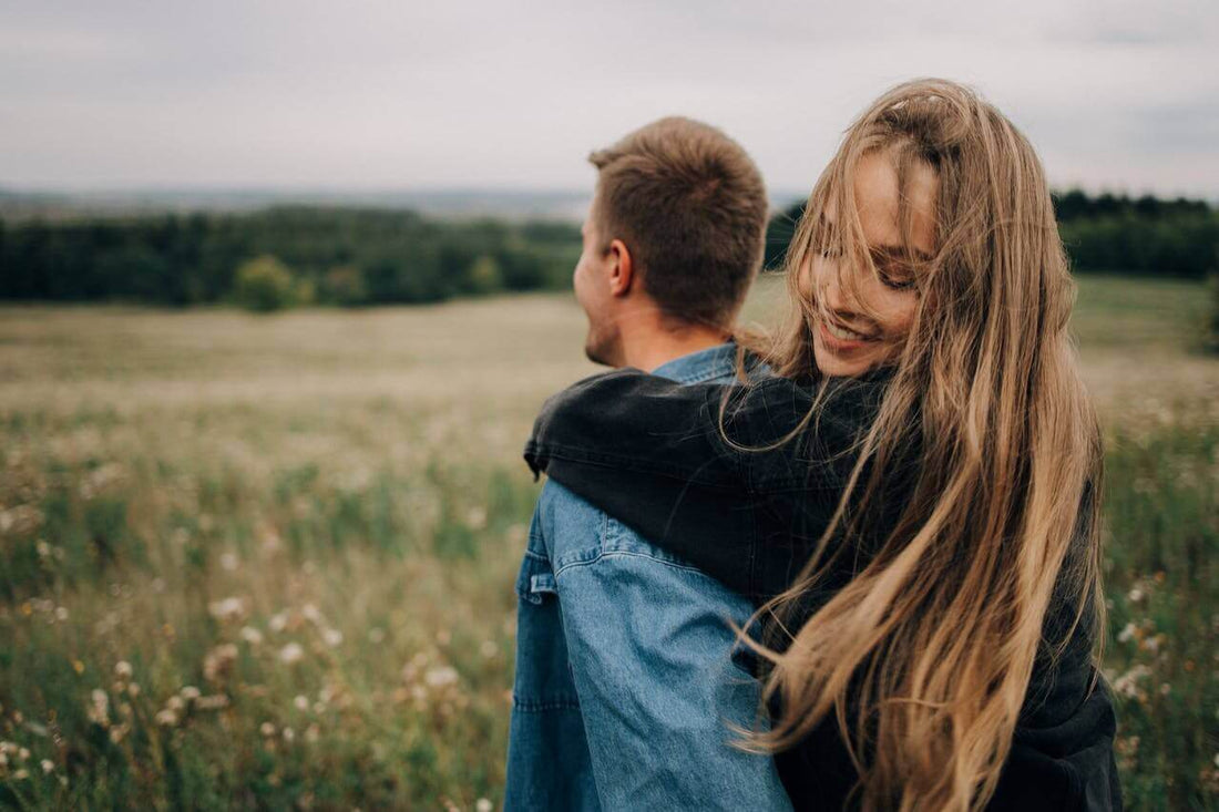 A happy couple embracing in a field, symbolizing the message to love yourself and each other.