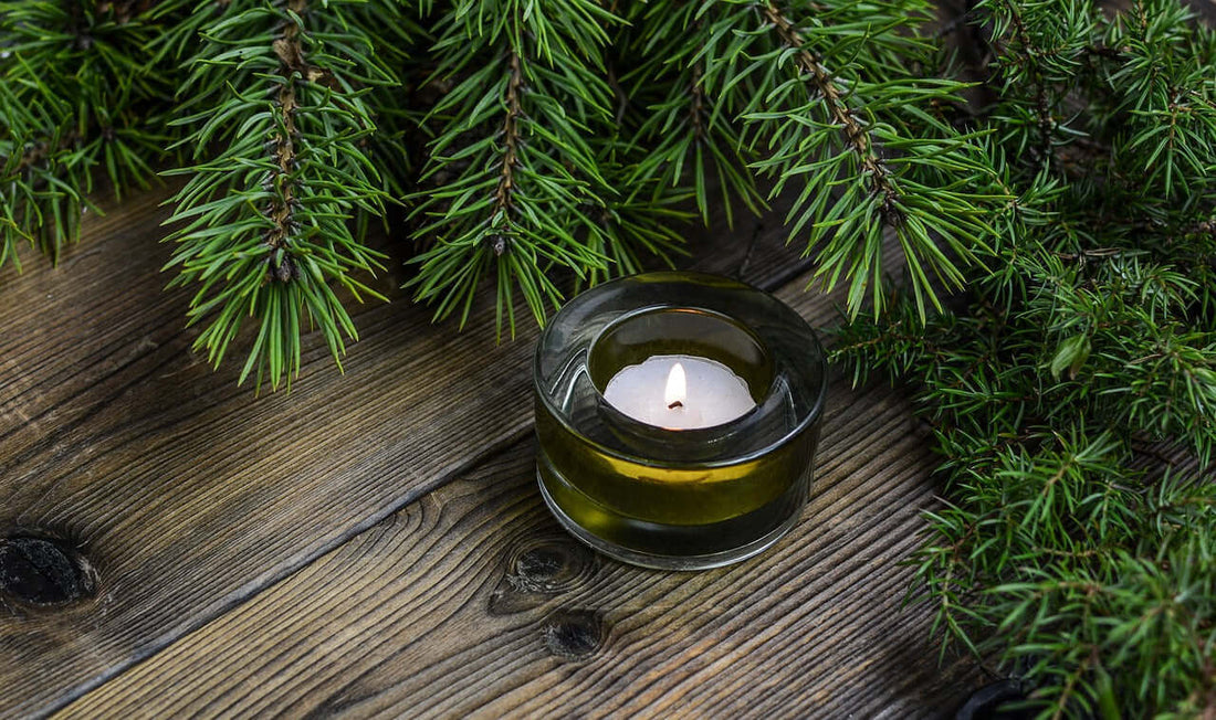 gifts of serenity collection featuring a candle surrounded by greenery on a wooden surface.