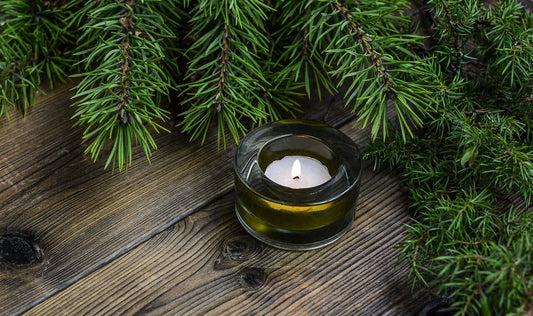 gifts of serenity collection featuring a candle surrounded by greenery on a wooden surface.