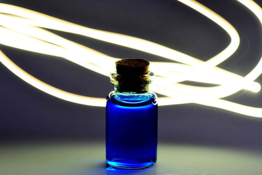 Blue glass bottles for sustainable wellness with a cork lid, illuminated by swirling light.