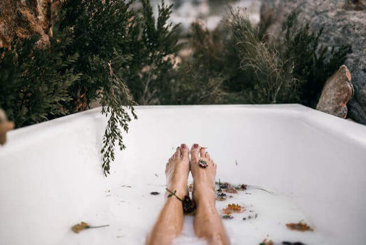 Relaxing feet in a bathtub surrounded by nature, promoting mineral baths for better sleep.