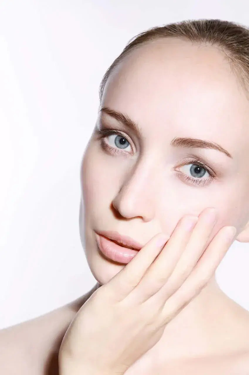 A woman gently touching her face, showcasing clear and healthy skin as part of the Skin Health Collection.